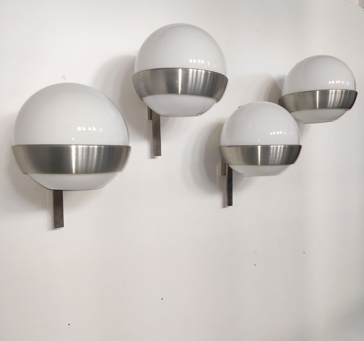 Quattro, 4, appliques, disegnate, PiaGuidettiCrippa, LUMI, LumiMilano. Struttura, acciaio, alluminio, satinato, paralume, sfera, vetro, lattimo, Italia, anni70, set, four, wall, lamps, designed, by, Pia, Guidetti, Crippa, for, Lumi Milano, Steel, satin-finish, aluminum, frame, milky, glass, sphere, shade, Italy, 1970s,